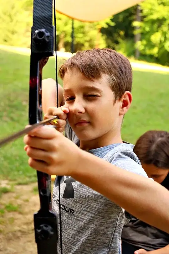 chlapec strieľa z luku v letnom tábore Fantázia